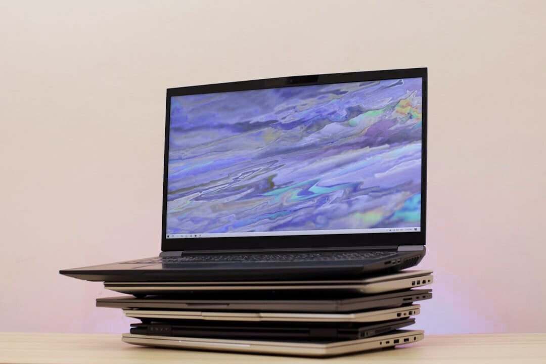 Stos laptopów HP różnych linii, na wierzchu otwarty model z kolorowym ekranem